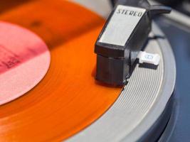 toonarm van platenspeler Aan oranje vinyl schijf foto