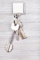 bundel van sleutels met sleutel keten Aan houten achtergrond foto
