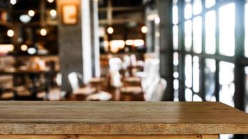 leeg donker houten tafel in voorkant van abstract wazig bokeh achtergrond van restaurant . kan worden gebruikt voor Scherm of montage uw producten. foto