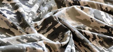 kleding stof met structuur van oekraïens leger korrelig camouflage. kleding met camo patroon in grijs, bruin en groen pixel vormen. officieel uniform van oekraïens soldaten foto