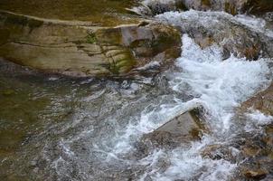 detailopname beeld van een klein wild waterval in de het formulier van kort streams van water tussen berg stenen foto