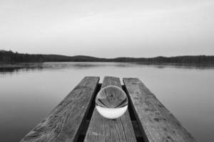 glas bal Aan een houten pier Bij een Zweeds meer Bij schemer in zwart en wit. natuur foto