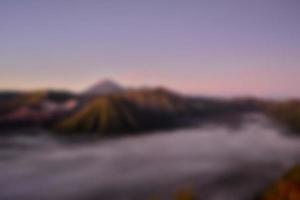 wazig visie van monteren bromo Bij zonsopkomst. vervagen berg achtergrond en natuur landschap foto