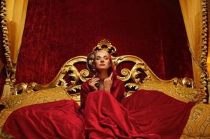 mooie vrouw met een carnaval masker zittend in bed foto