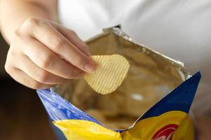 hand- houden aardappel chips met tussendoortje zak foto