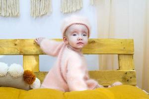 schattig weinig baby meisje met blauw ogen in roze zacht jurk, terug visie. openhartig kind portret Bij huis. foto