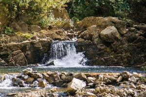 visie van een klein mooi waterval tussen rotsen en herfst Woud. foto