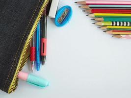 de top visie van schrijfbehoeften in school- Tassen en potloden geregeld Aan een wit achtergrond. foto