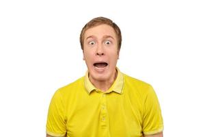 verraste jonge man met grappige gezichtsuitdrukking in geel t-shirt, witte geïsoleerde achtergrond foto