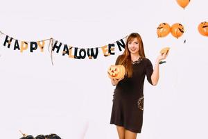 jong vrouw met zwart pompoen in halloween decoratie foto