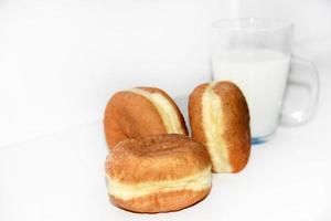 heerlijk zoet broodjes met jam en een glas van melk Aan een wit achtergrond. een heerlijk ontbijt van prachtig gebakken broodjes en melk. foto