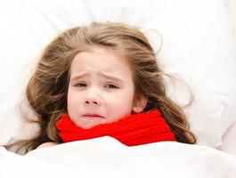 ziek meisje liggend in het bed in rode sjaal foto