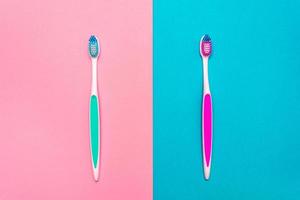 dichtbij omhoog van blauw en roze plastic tandenborstels met roze en blauw varkenshaar Aan roze en blauw achtergrond foto