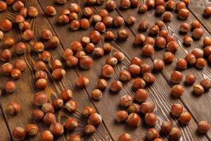 hazelnoten met schelpen gelijkmatig verspreide Aan bruin houten tafel oppervlakte foto