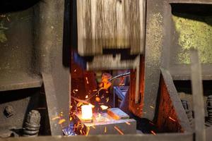 detailopname afbeelding van heet staal smeden werkwijze met groot mechanisch hamer machine foto