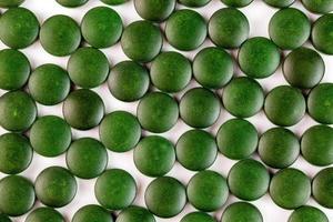 veel groen biologisch spirulina tablets gelegd willekeurig in een laag Aan vlak wit oppervlakte foto