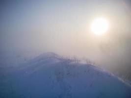 winter sneeuw heuvel met voetafdrukken in diep sneeuw Bij mistig ochtend- foto