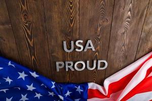 woorden Verenigde Staten van Amerika trots gelegd met zilver metaal brieven Aan bruin houten oppervlakte met vlag van Verenigde staten van Amerika foto