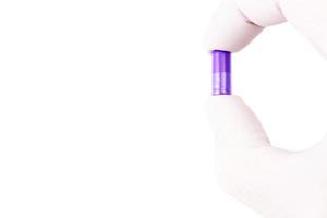 hand- in medisch handschoen Holding proton Purper kleur biologisch med capsule geïsoleerd Aan wit achtergrond detailopname foto