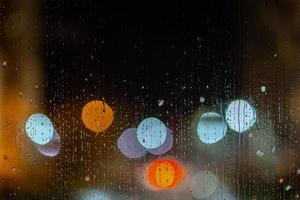 een abstract achtergrond van nacht straat lichten bokeh door nat glas, detailopname met selectief focus foto