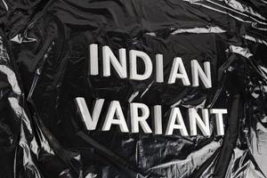 woorden Indisch variant gelegd met zilver metaal brieven Aan verfrommeld zwart plastic zak achtergrond in diagonaal perspectief foto