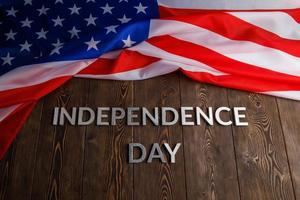de woorden onafhankelijkheid dag gelegd Aan bruin houten planken oppervlakte met verfrommeld Verenigde staten van Amerika vlag foto