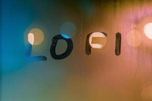 de woord lofi geschreven door vinger Aan nacht nat venster glas, blauw en oranje kleuren foto