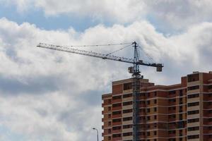 gebouw werkwijze van groot woon- appartement gebouw met kraan Aan bewolkt lucht achtergrond foto