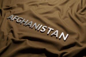 de woord afghanistan gelegd met zilver metaal brieven Aan verfrommeld bruinen khaki canvas kleding stof foto