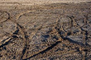 droog zand en modder grond met veel aarde fiets sporen Bij daglicht foto