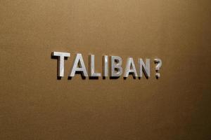 de vraag taliban gelegd met zilver metaal brieven Aan ruw bruinen khaki canvas kleding stof foto
