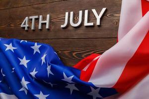 de woorden 4e juli en verfrommeld Verenigde Staten van Amerika vlag Aan vlak getextureerde houten oppervlakte achtergrond foto