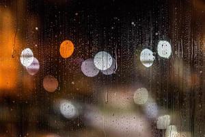 een abstract achtergrond nacht straat lichten bokeh door nat glas met water vlekken, detailopname met selectief focus foto