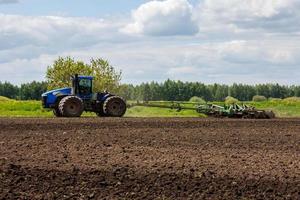 blauw trekker met dubbele wielen trekken schijf eg met rol mand Bij heet zonnig dag foto