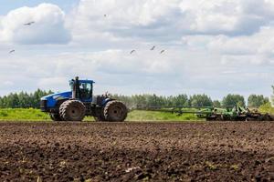 blauw trekker met dubbele wielen trekken schijf eg met rol mand Bij heet zonnig dag foto