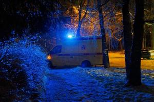 Russisch ambulance auto het rijden Aan straat achter struiken Bij winter nacht foto