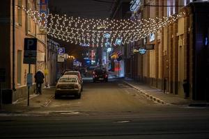 tula, Rusland - januari 1 2019. Mens plassen in uitschot bak Aan nacht straat Bij nieuw jaar nacht in centrum van tula. foto