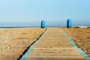 houten loopbrug Aan de strand met twee afval bakken in de achtergrond. horizontaal beeld foto