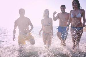 gelukkig mensen groep hebben pret en rennen Aan strand foto