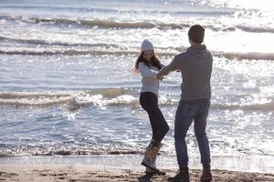 liefhebbend jong paar Aan een strand Bij herfst zonnig dag foto