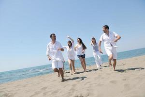 gelukkig mensen groep hebben pret en rennen Aan strand foto