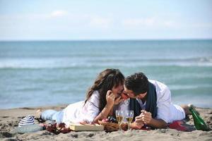 jong paar genieten van picknick Aan de strand foto