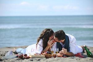 jong paar genieten van picknick Aan de strand foto