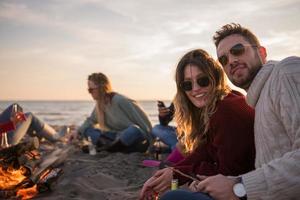 paar genieten van met vrienden Bij zonsondergang Aan de strand foto