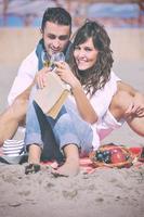 jong paar genieten van picknick Aan de strand foto