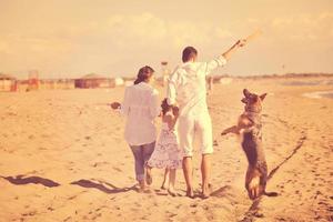 gelukkig familie spelen met hond Aan strand foto