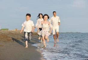 gelukkig jong familie hebben pret Aan strand Bij zonsondergang foto