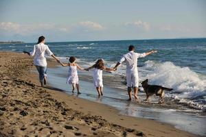 gelukkig familie spelen met hond Aan strand foto