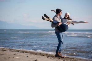 liefhebbend jong paar Aan een strand Bij herfst zonnig dag foto