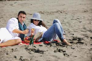 jong paar genieten van picknick Aan de strand foto